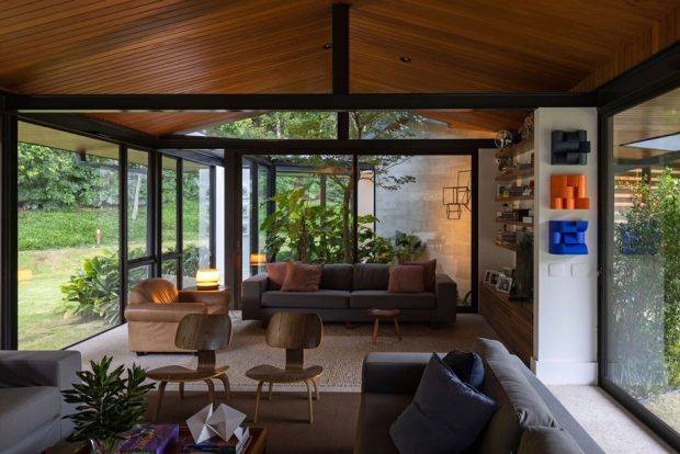 The living room has a glass wall overlooking the garden.