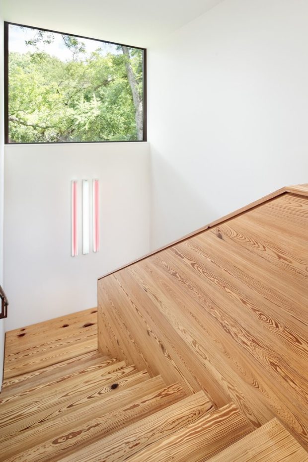 The wooden staircase has a skylight on the wall for viewing the view.